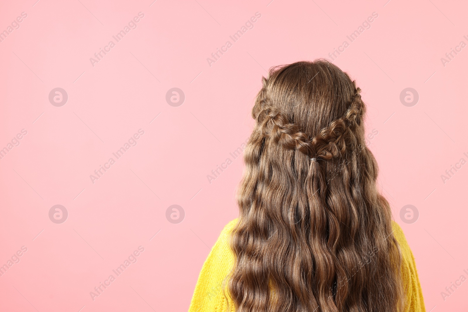 Photo of Little girl with braided hair on pink background, back view. Space for text