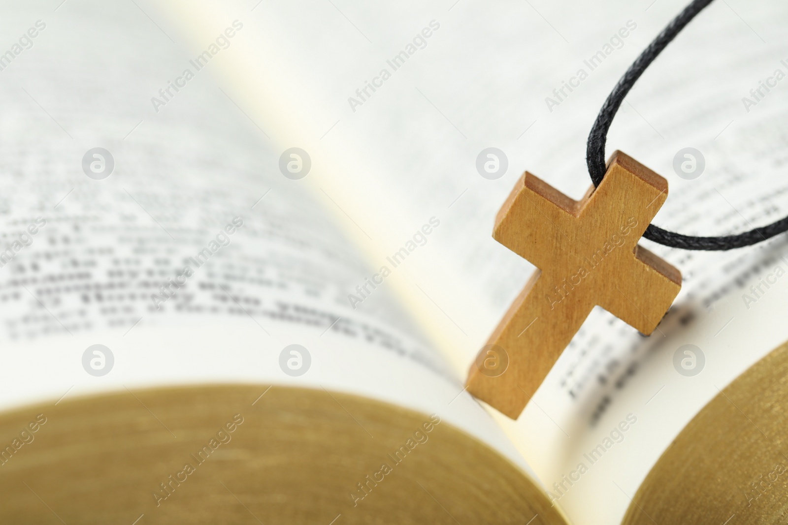 Photo of Christian cross on open Bible, closeup view