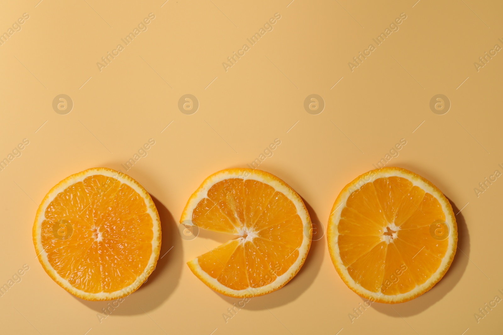 Photo of Slices of juicy orange on beige background, flat lay. Space for text