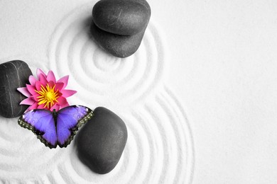 Image of Beautiful butterfly, flower and stones on white sand with pattern, flat lay. Zen concept