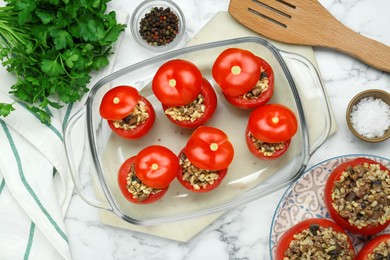 Photo of Delicious stuffed tomatoes with minced beef, bulgur and mushrooms in glass baking dish on white table, flat lay