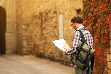 Traveler with map on city street, back view
