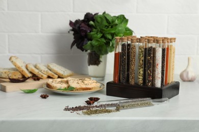 Glass tubes with different spices and plate of sandwiches on kitchen counter
