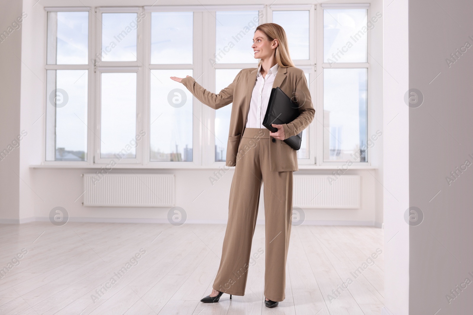 Photo of Happy real estate agent with leather portfolio showing new apartment