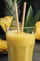 Photo of Tasty pineapple smoothie and fruit on table, closeup