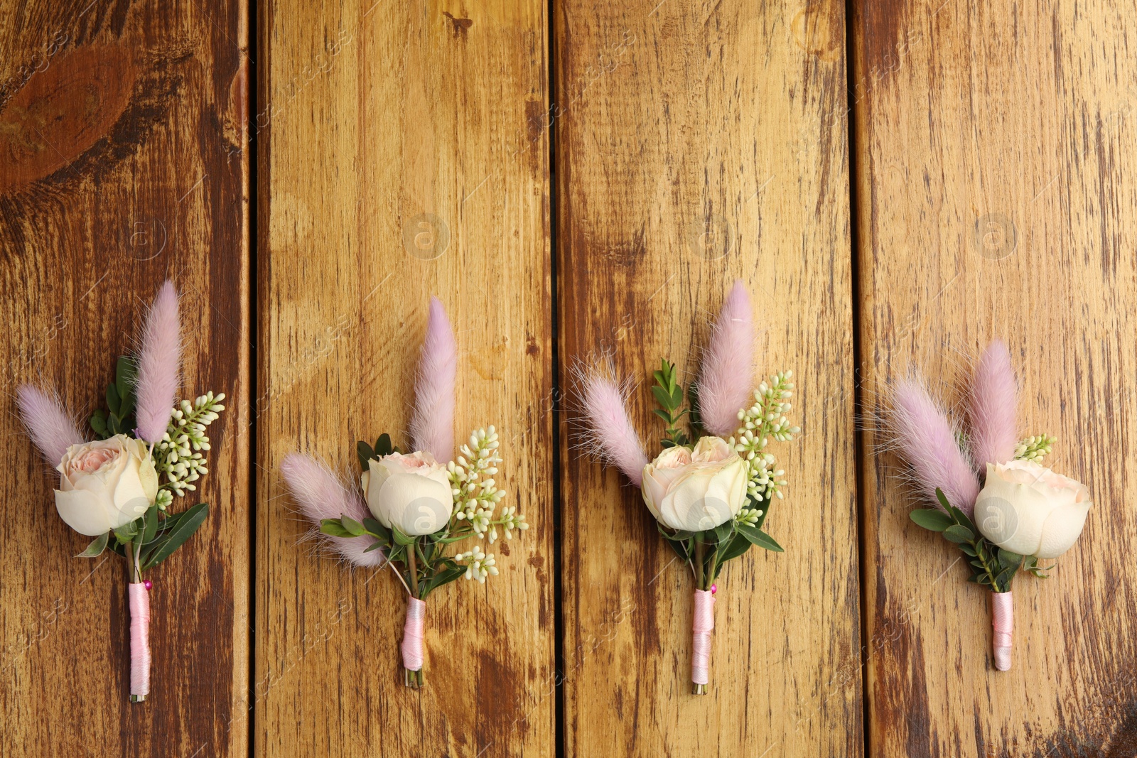 Photo of Many stylish boutonnieres on wooden table, flat lay. Space for text