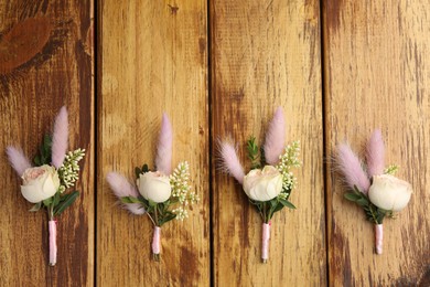 Many stylish boutonnieres on wooden table, flat lay. Space for text
