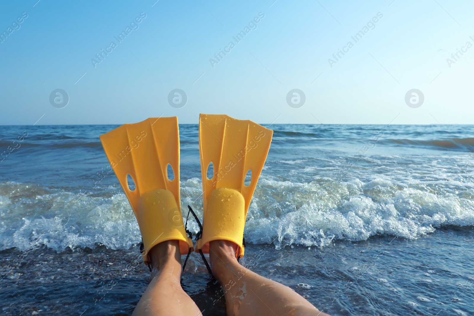 Photo of Woman in flippers near sea on beach, closeup