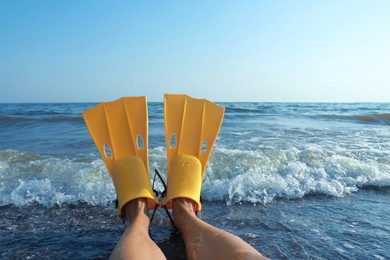 Photo of Woman in flippers near sea on beach, closeup