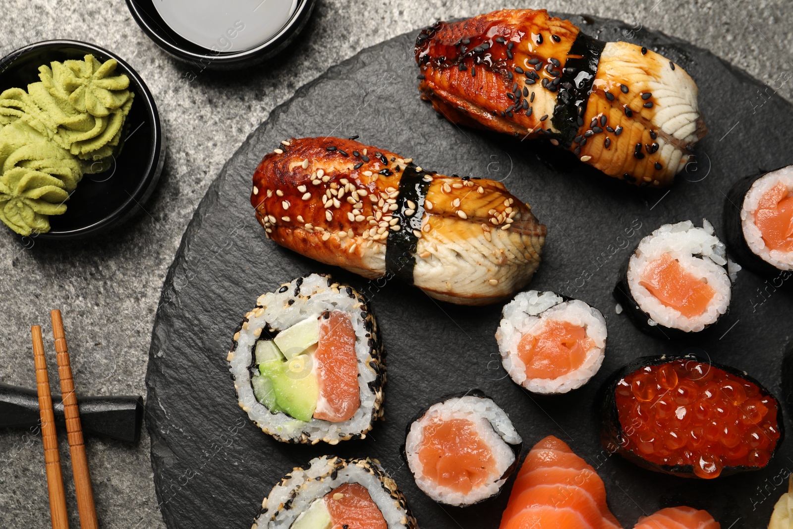 Photo of Set of delicious sushi rolls on dark grey table, flat lay