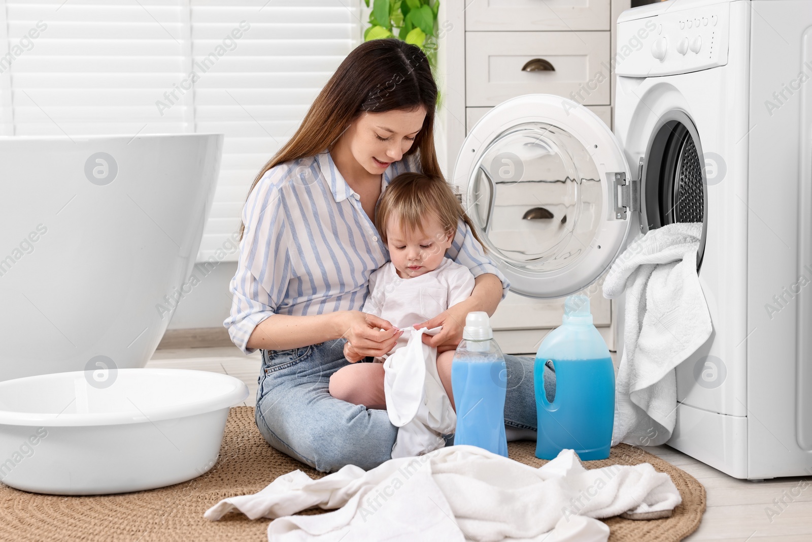 Photo of Mother with her daughter washing baby clothes in bathroom