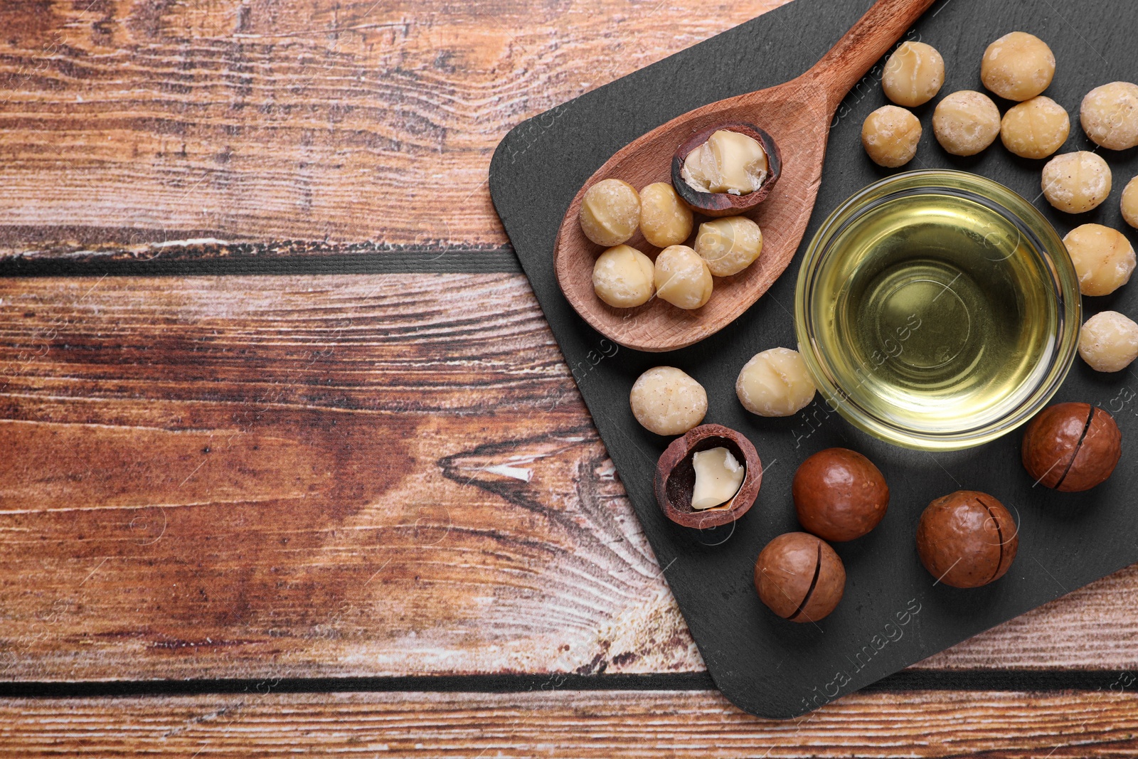 Photo of Delicious organic Macadamia nuts and natural oil on wooden table, top view