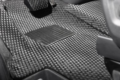 Photo of Black rubber car floor mat in auto, closeup