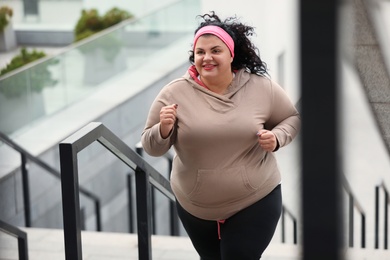 Photo of Beautiful overweight woman running up stairs outdoors