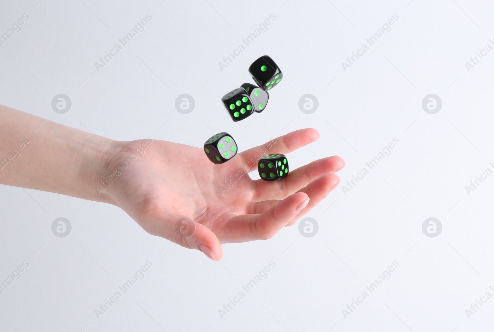 Photo of Woman throwing game dices on white background, closeup