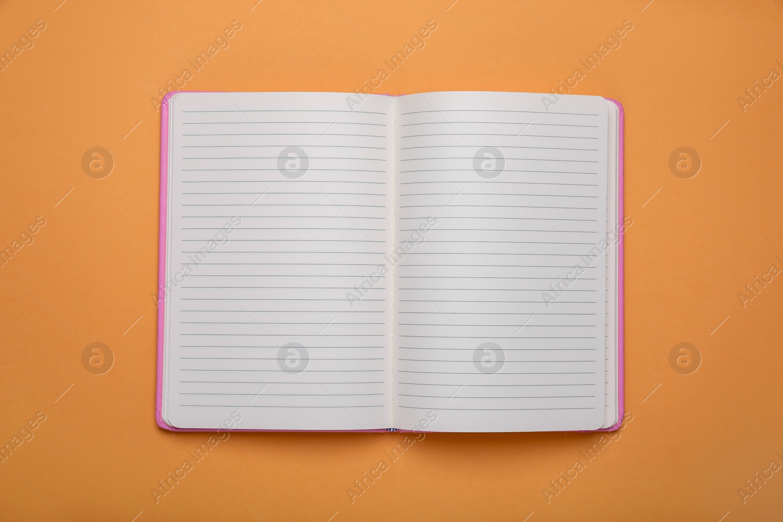 Photo of Open office notebook on pale orange background, top view