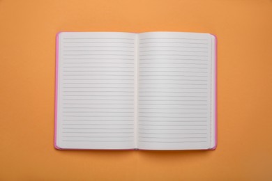 Photo of Open office notebook on pale orange background, top view