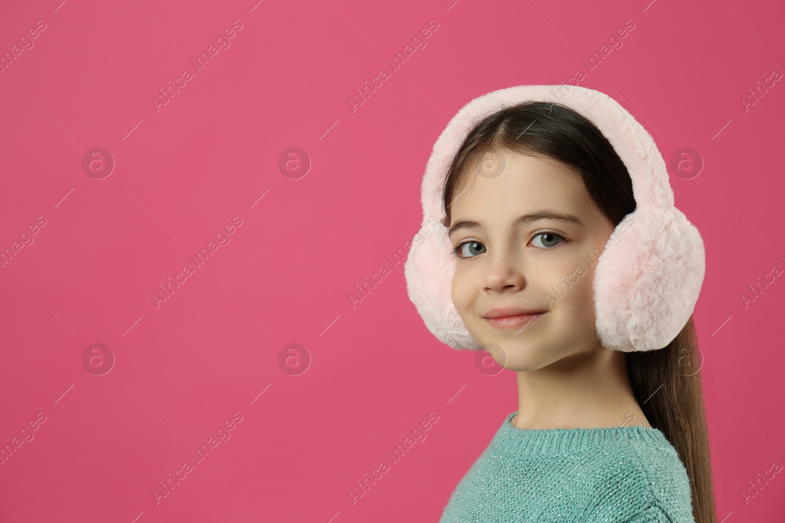 Photo of Cute little girl wearing stylish earmuffs on pink background. Space for text