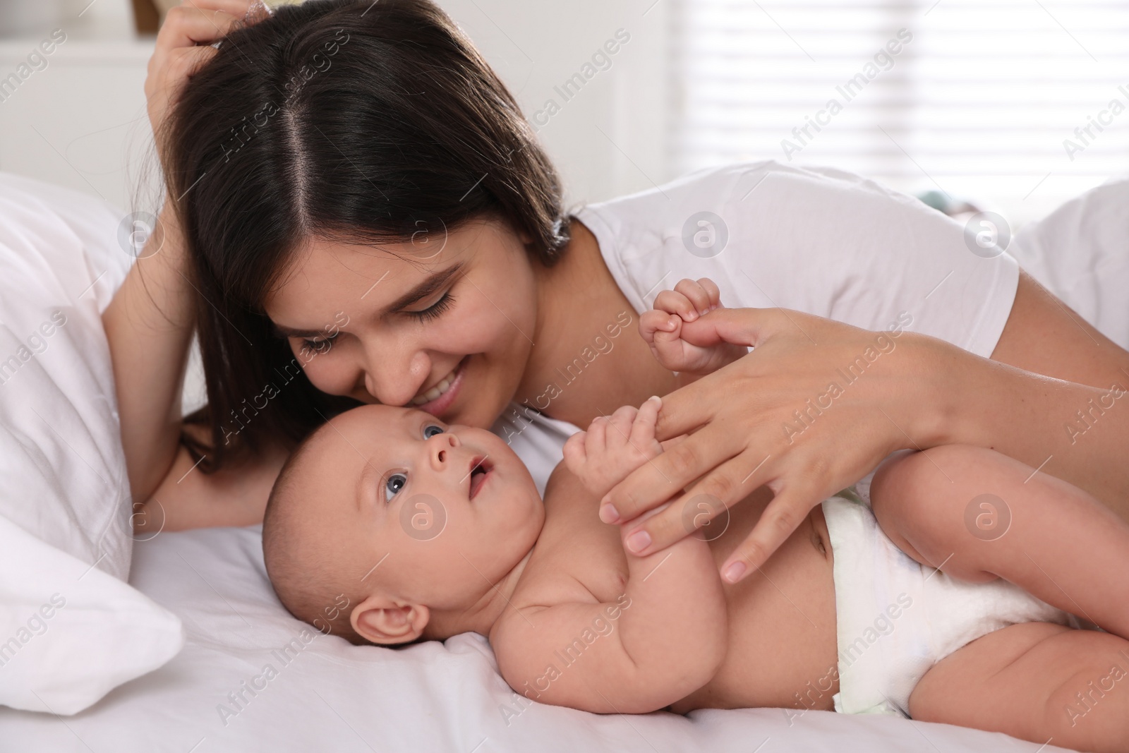 Photo of Happy young mother with her cute baby on bed at home