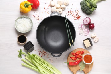 Photo of Wok, chopsticks and different products on white wooden table, flat lay