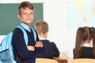 Little boy with backpack in school classroom