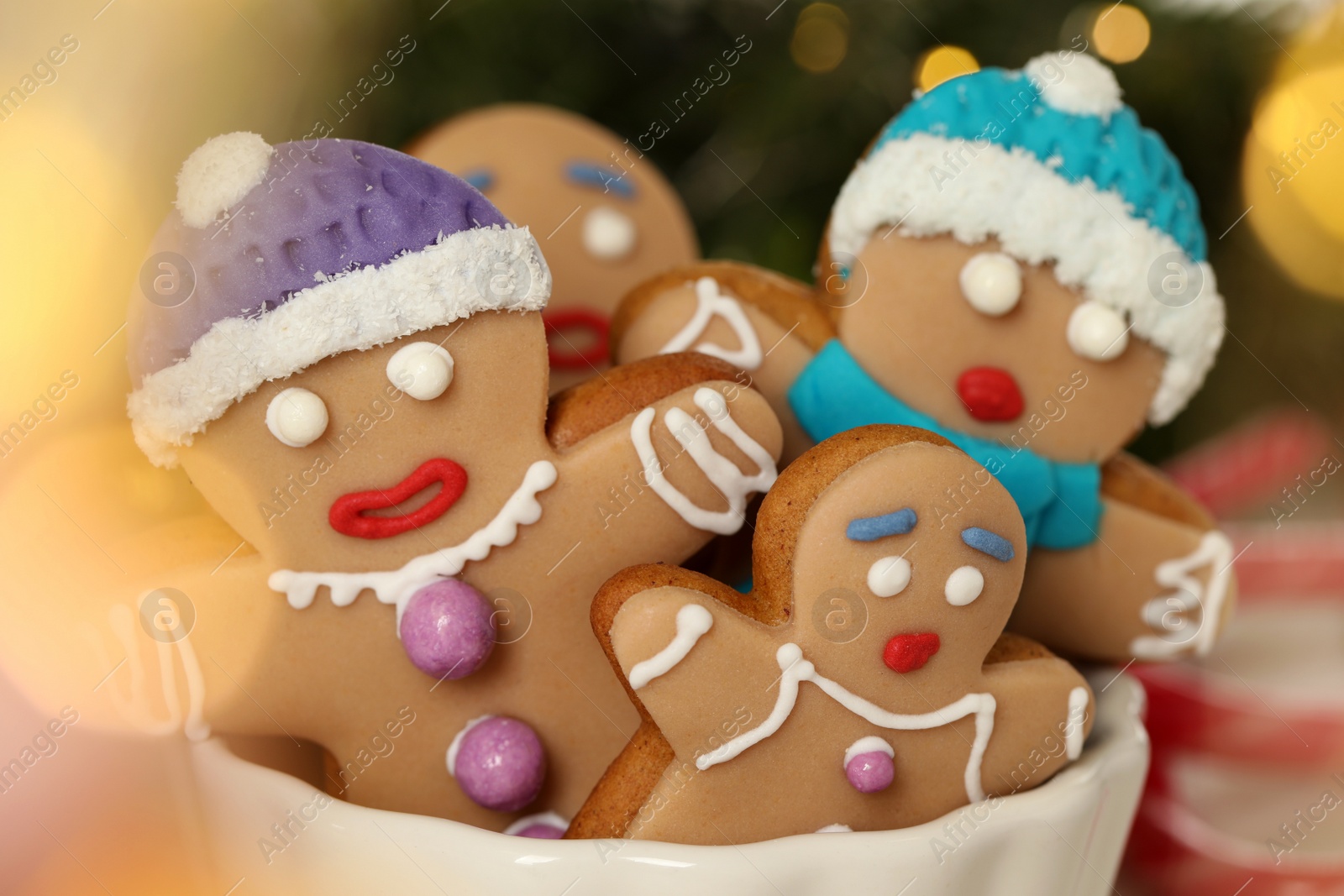 Photo of Delicious homemade Christmas cookies in bowl against blurred festive lights, closeup