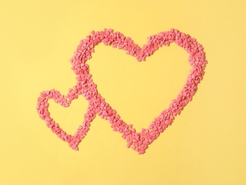 Photo of Hearts made of bright sprinkles on yellow background, flat lay