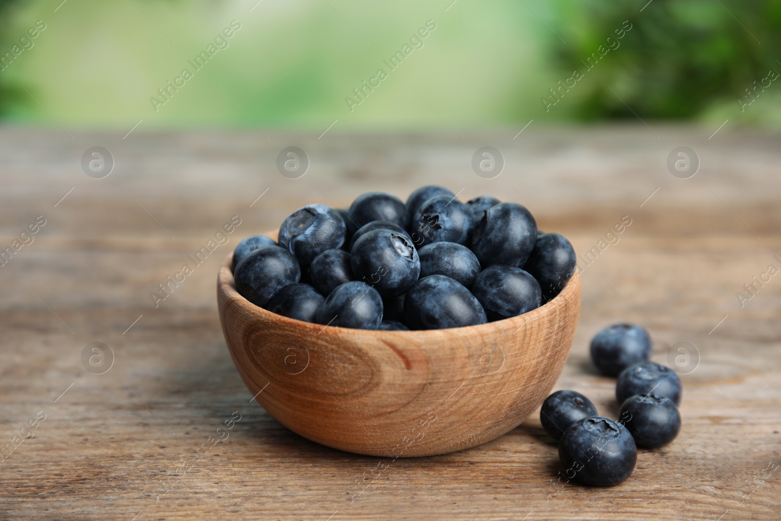 Photo of Bowl of fresh blueberries on wooden table