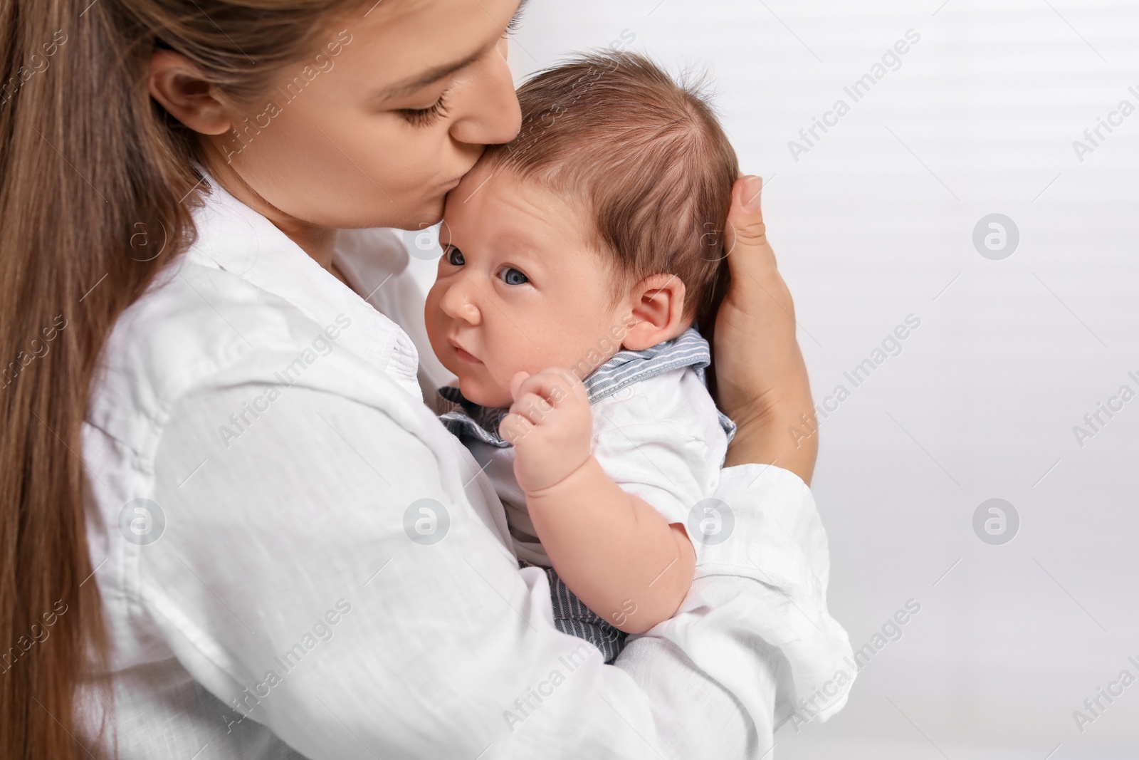 Photo of Mother kissing her cute newborn baby indoors, space for text