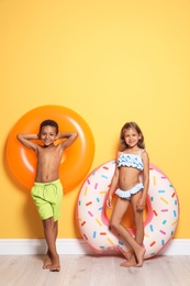 Photo of Cute little children with bright inflatable rings near color wall