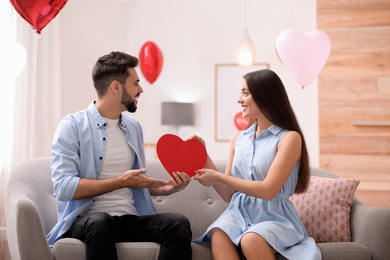 Lovely couple in living room decorated with heart shaped balloons. Valentine's day celebration