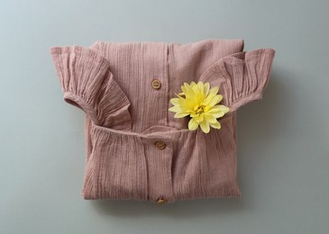 Stylish child clothes and flower on grey background, top view