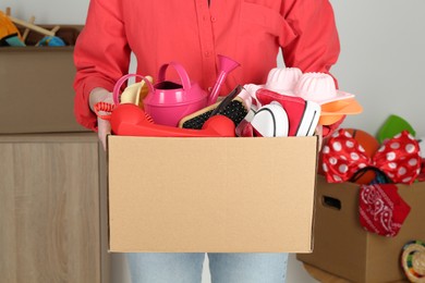 Woman holding box of unwanted stuff indoors, closeup