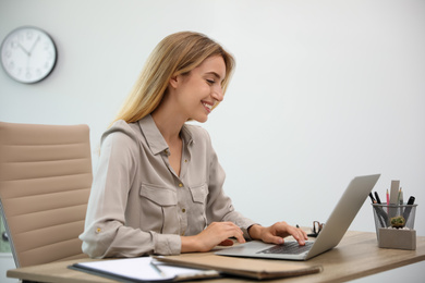 Pretty young woman working with laptop in office