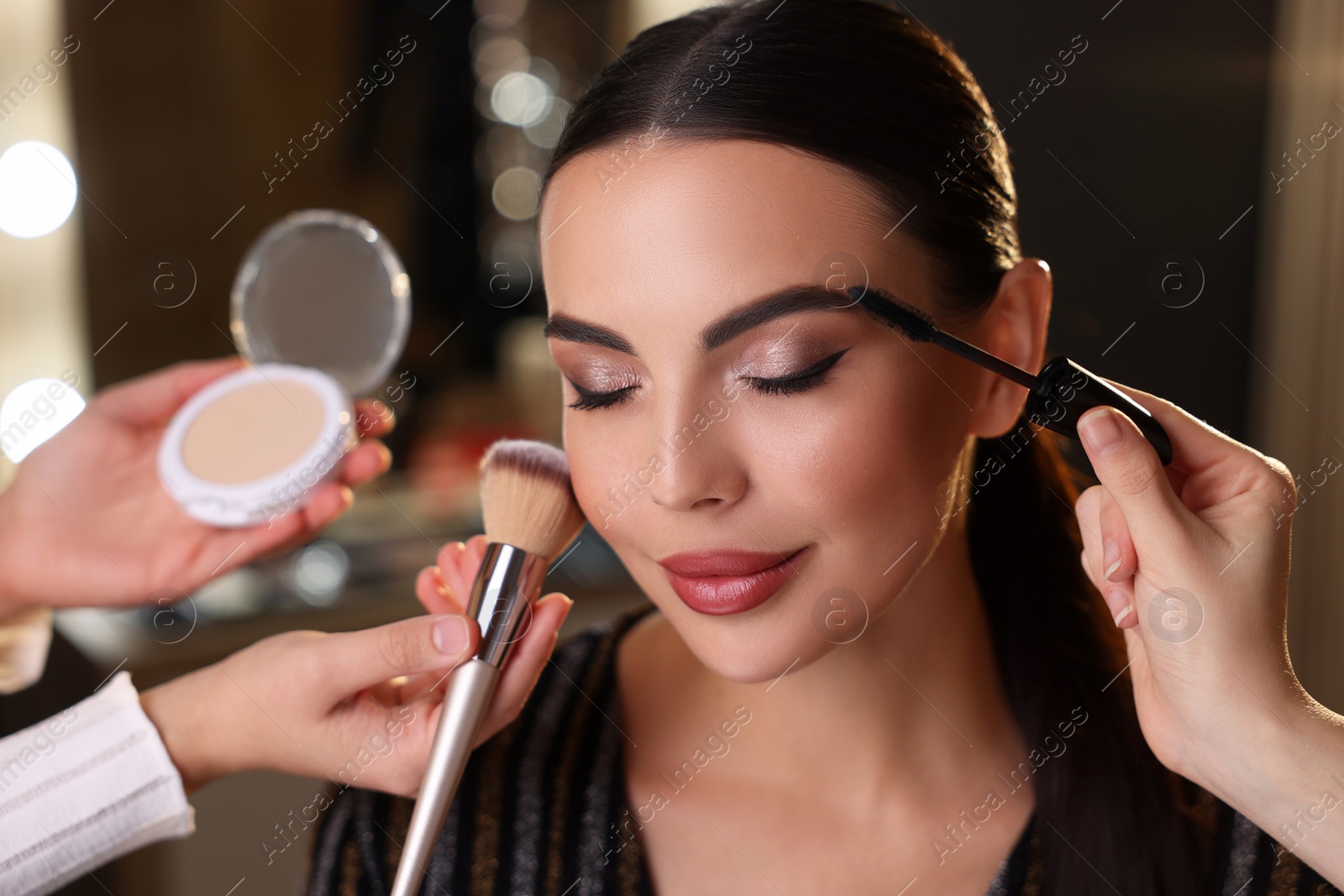 Photo of Makeup artists working with beautiful woman in dressing room