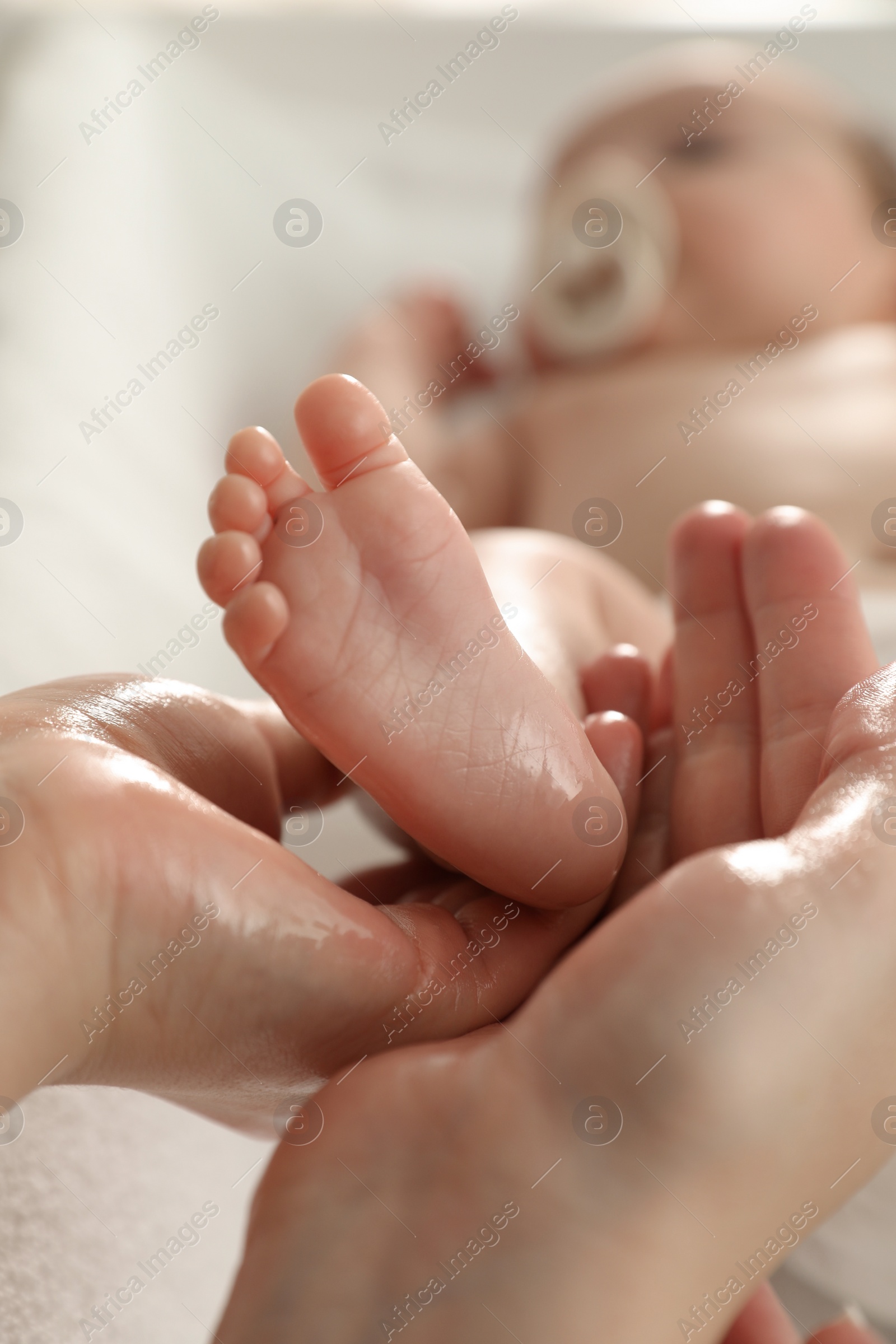 Photo of Mother massaging her cute baby with oil, closeup