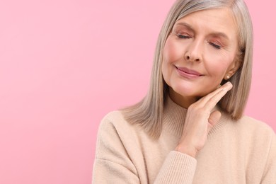 Portrait of beautiful middle aged woman on pink background, space for text