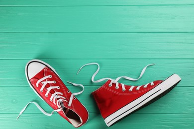 Pair of red sneakers on turquoise wooden table, flat lay. Space for text