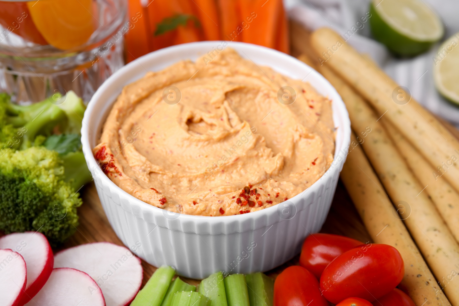 Photo of Delicious hummus, grissini sticks and fresh vegetables, closeup view