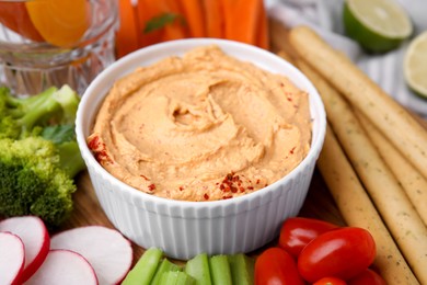 Delicious hummus, grissini sticks and fresh vegetables, closeup view