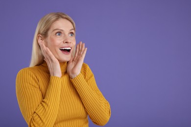 Portrait of surprised woman on violet background, space for text