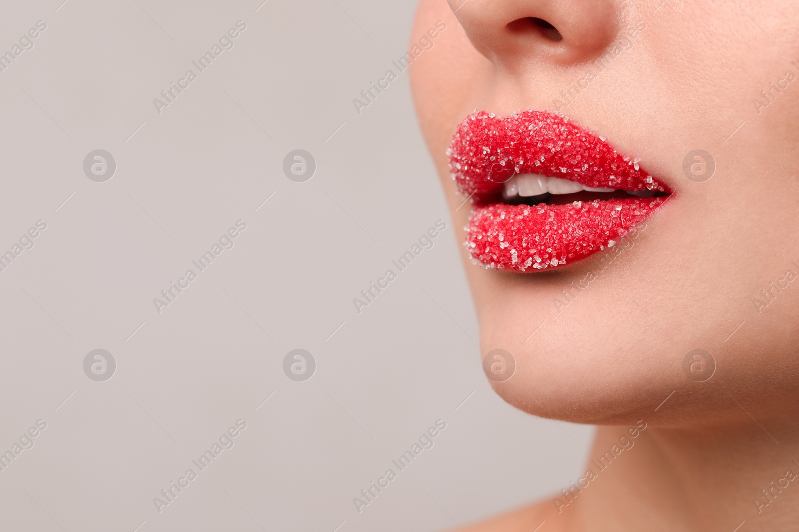 Photo of Young woman with beautiful lips covered in sugar, on light background, closeup. Space for text