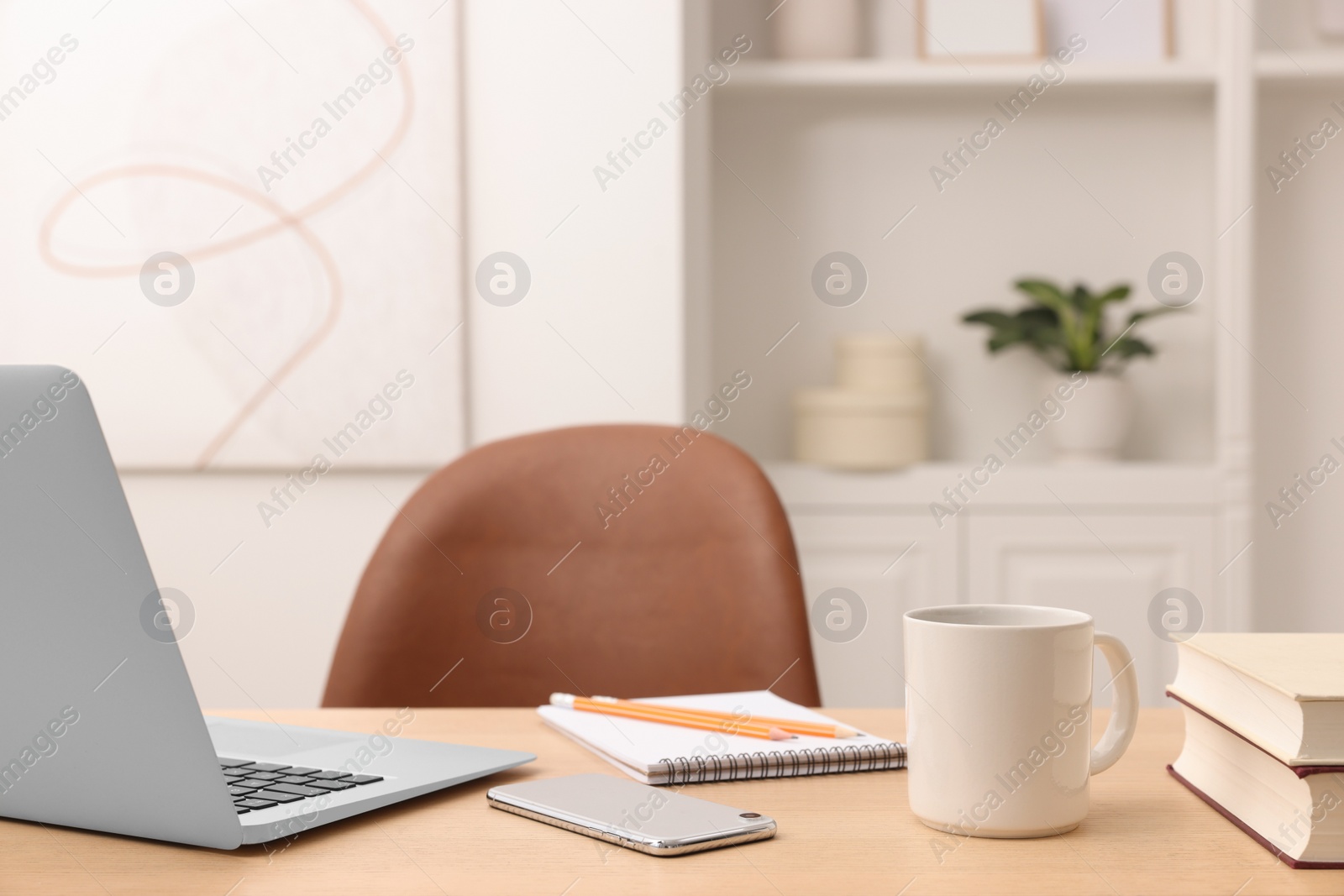 Photo of Home office. Laptop, cup, smartphone and stationery on wooden desk indoors. Space for text