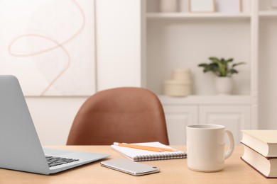 Home office. Laptop, cup, smartphone and stationery on wooden desk indoors. Space for text