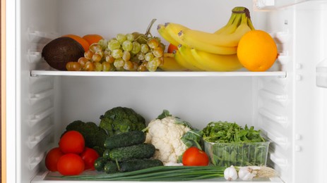 Photo of Open refrigerator with different fresh vegetables and fruits