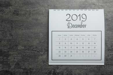 Photo of December 2019 calendar on grey stone background, top view. Space for text