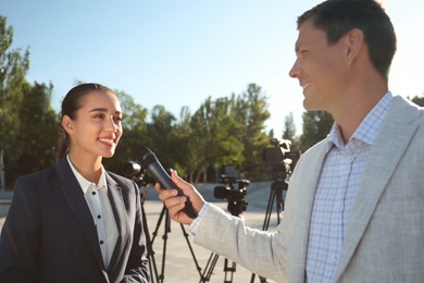 Photo of Professional journalist interviewing young woman on city street