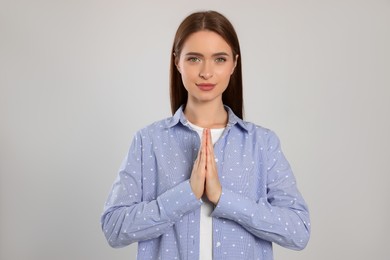 Photo of Woman with clasped hands praying on light grey background
