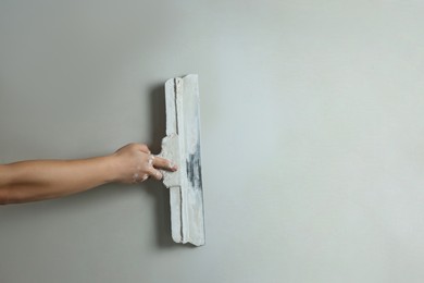 Professional worker plastering wall with putty knife, closeup