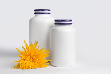 Photo of Plastic medicine bottles and yellow flower on white background. Medicament